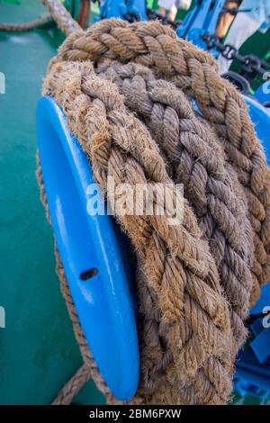 Ship shabby wicker thick rope wound on an iron hook. Moored ship. Horizontal. Stock Photo