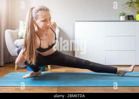Young smiling woman doing Marichyasana yoga pose at home Stock Photo