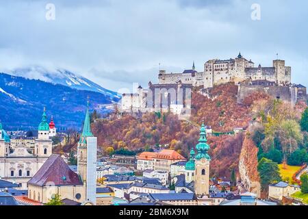 The medieval castle of Hohensalzburg towers the old town of Salzburg with its historical mansions, tall belfries and foggy Alps on the background, Aus Stock Photo