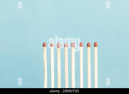 Eight unused matchsticks against a blue background. Stock Photo