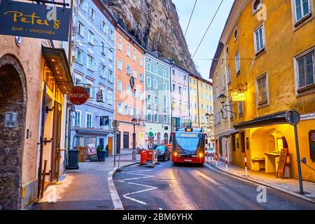 SALZBURG, AUSTRIA - MARCH 1, 2019: The modern trolleybus drives along curved Gstattengasse street with high colorful medieval buildings in Altstadt (O Stock Photo