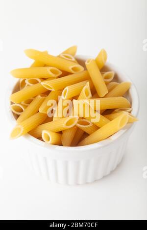 Penne pasta photographed in a ramekin dish on a white background Stock Photo