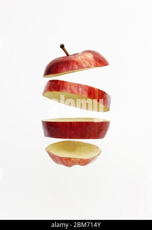 Fresh red golden delicious apple cut into slices floating isolated on white background. Stock Photo
