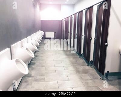 Public toilet restroom with doors and urinals in a row Stock Photo