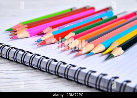 Color pencils lying on a pad with a spiral. Gray natural background, blur Stock Photo