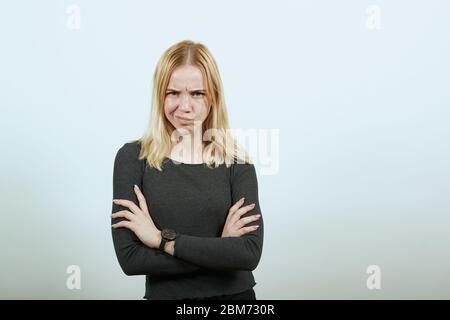 Young Blonde Woman In Black Sweater On White Background, Annoyed Girl Angry Stock Photo