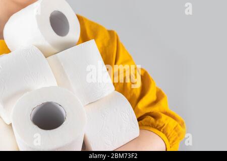 Female hands carrying many rolls of toilet paper in fear of an outbreak of crown virus closing stores. Basic hygiene article shortage Stock Photo