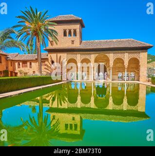 GRANADA, SPAIN - SEPTEMBER 25, 2019: Historic ornate building of Partal Palace portico (Alhambra) with beautiful arches, Ladies tower and pool on the Stock Photo