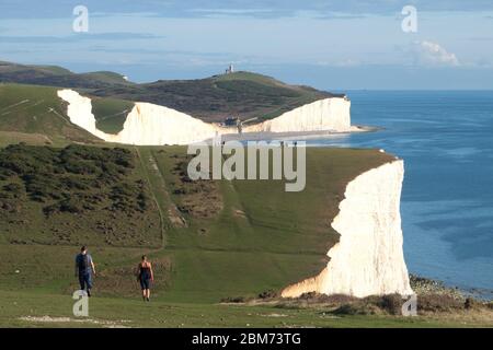 Walkers on the Seven Sisters cliff path, part of the South Downs Way in East Sussex (also shows Birling Gap and the Belle Tout Lighthouse) Stock Photo