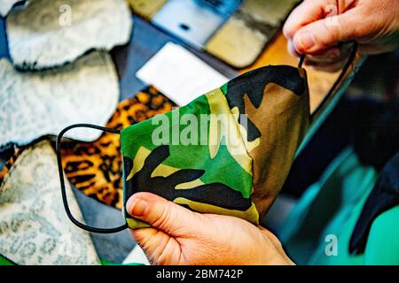 A view of  an army fabric face mask.From 1st June masks are required to be worn on public transport. In a Sewing workshop Aladdin makes unique masks made with own design and different fabrics. Stock Photo