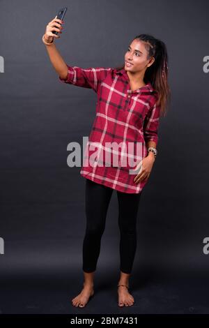 Full body shot of young beautiful Asian hipster woman taking selfie Stock Photo