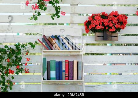 Book stack of step to success concept, flowering plants in pots on background. Vintage books with empty labels with free copy space on a white shelf. Stock Photo