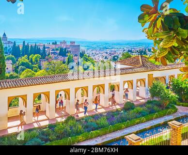 GRANADA, SPAIN - SEPTEMBER 25, 2019: People walk the arcade of Patio of  Irrigation Ditch of Generalife with topiary garden on the foreground and Alha Stock Photo