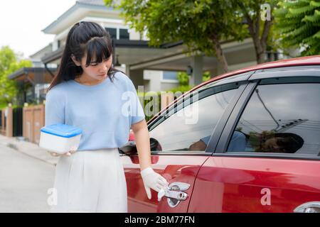 Asian woman disinfecting door handle of red car by disinfectant disposable wipes from box. Prevent the virus and bacterias, Prevent covid19, corona vi Stock Photo