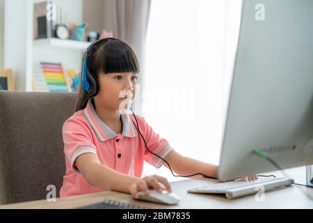 Asian girl student video conference e-learning with teacher on computer in living room at home. Homeschooling and distance learning ,online ,education Stock Photo