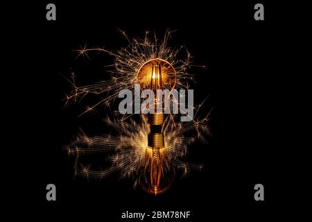 Glowing sparkler behind a retro light bulb Stock Photo