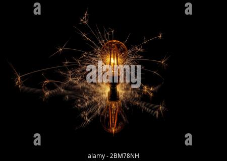 Glowing sparkler behind a retro light bulb Stock Photo