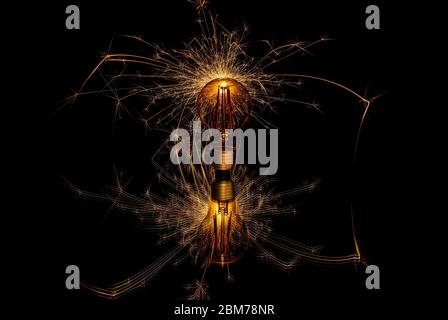 Glowing sparkler behind a retro light bulb Stock Photo