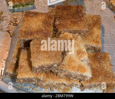 Tray in the showcase with turkish traditional dessert, baklava, cataif sweet honey deserts during food festival, street food specialties Stock Photo