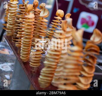 Fried swirl potato spiral on a stick during street food festival. Fast food Stock Photo