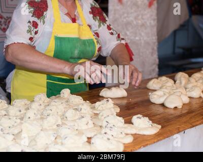 Traditional east european (romanian, hungarian, bulgarian, moldovian) woman in authentic clothing kneading bread dough for 'poale'n brau', a tradition
