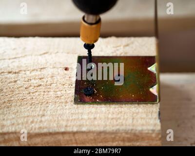 Assembling wooden frame of a building using metal fasteners using a screwdriver Stock Photo