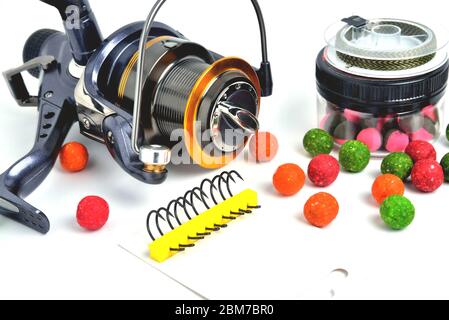 Fishing coil, carp hooks colored boilies, braided cord, on white background, close-up Stock Photo
