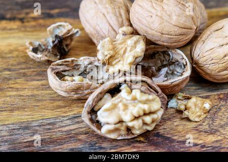 Walnuts on the wooden background closeup. Fresh big walnuts, whole and open, healthy fruit with protein, vitamins and minerals. Macro. Stock Photo