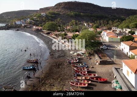 Youth helping fishermen launching traditional wooden fishing boats, Cidade Velha on the island of Santiago, Cape Verde / Cabo Verde Stock Photo