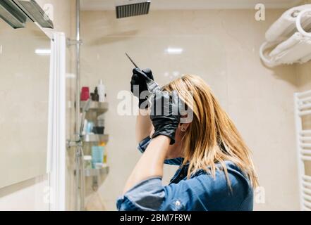 A woman dyes her hair in her home bathroom. Stock Photo