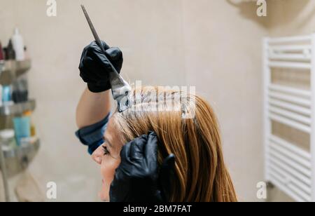 A woman dyes her hair in her home bathroom. Stock Photo