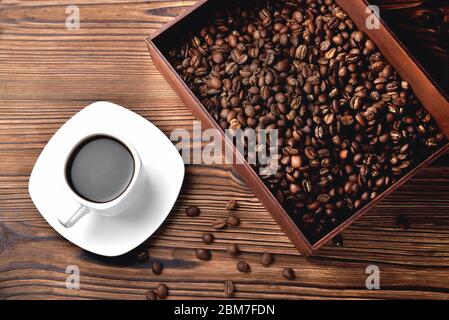 white coffee cup, morning side light coffee beans wooden box with coffee, top view natural wooden background close-up Stock Photo