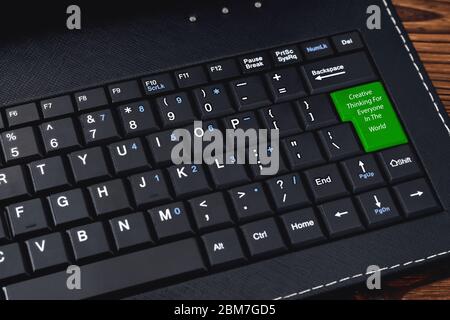 Computer keyboard. The "Creative Thinking For Everyone In The World " keyboard button is green for the network community concept. close-up Stock Photo