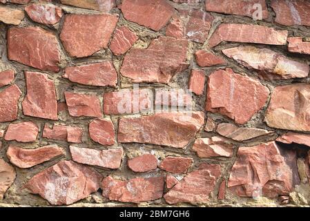 The wall of large raw granite stones of red color, background granite non-uniform Stock Photo