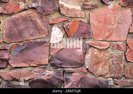 The wall of large raw granite stones of red color, background granite non-uniform Stock Photo