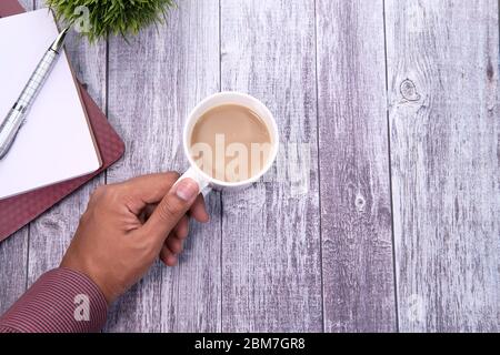 young man hand holding tea cup on table, top view. Stock Photo