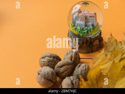 Yellow autumn leaves with nuts and glass sphere on the orange background. Copy space. Flat lay. Top view. Space for text. Greetings composition. Stock Photo