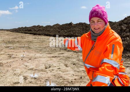 RODBY, DENMARK - MAY 06, 2020:  An enthusiastic archaeologist from Museum Lolland-Falster in Denmark, Jannice Kristiansen, at the  1 km long and 15 meter wide excavation pit which have revealed a 2.000 years old Iron Age defence belt at the soon to come Fehmernbelt Tunnel  construction site in the south-eastern  Denmark at the Baltic Sea shoreline. The defence line consist of some 5.000 holes, probably with hidden sharp oak spikes so an invading force coming from the sea, maybe from Northern Germany, would be injured by spikes penetrating their feet, or horses would plunge to the ground. The e