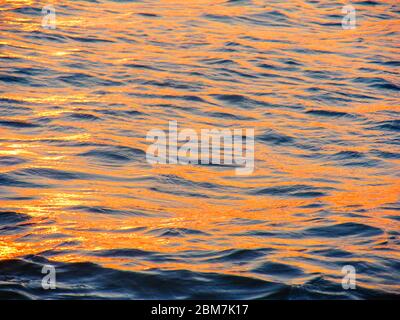 Small waves reflecting the golden light of the setting sun in the eastern part of Maputo Bay, Southern Mozambique Stock Photo