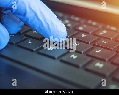 Online quarantine training. Remote online work. Coronovirus. Epidemic. Hands in protective medical gloves are typing on the keyboard. Stock Photo