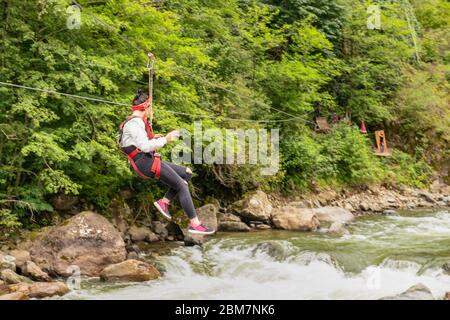 Rear view of tourist girl gliding on the zip line trip on Firtina valley, Rize, Turkey Stock Photo