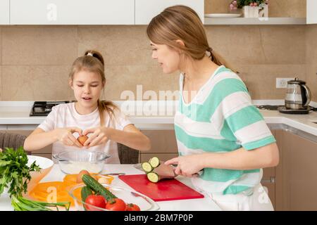 Mother and daughter cook at home. Making cookies, kitchen interior, healthy food concept. Happy, child.