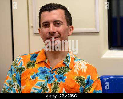 Happy young handsome tourist man sitting inside subway train Stock Photo