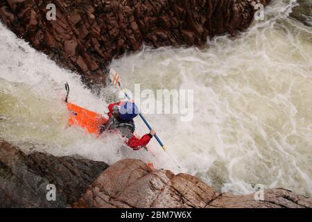 Female University Kayaker paddling over a waterfall (Triple Step) in a Z-one Kayak on the Etive River, Glen Coe, Scottish Highlands, Scotland, UK Stock Photo