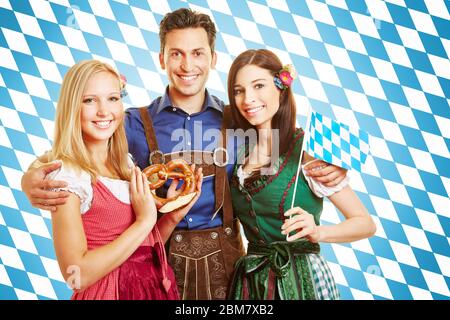 Laughing man and two smiling women in Bavarian costume with dirndls and leather pants Stock Photo