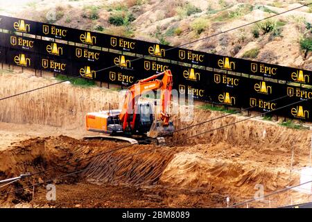 Orange tata hitachi excavator digging a dirt ramp with epic boards at a multi story construction real estate project Stock Photo