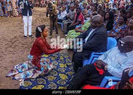 Marie Asumani, a bride-to-be, hands her father an envelope of cash to fulfill her dowry. (Françoise Mbuyi, GPJ DRC) Stock Photo