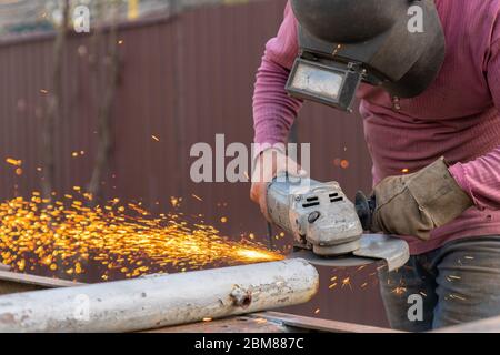 Craftsman sawing metal with disk grinder in the backyard Stock Photo