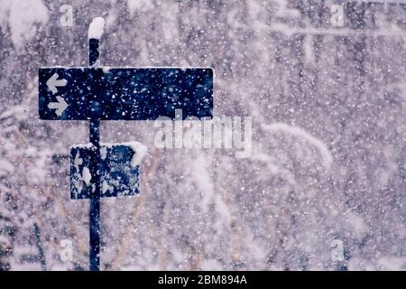 Blue sign with arrows in the middle of the snowfall of Bariloche Argentina. The sign says New Constitution. Stock Photo