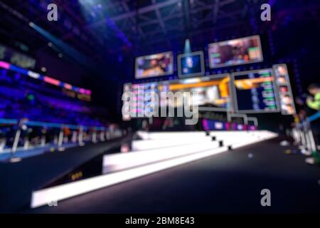 Blurred background of an esports event - Big illuminated main stage of a computer games tournament located on a big stadium. Tribunes are full of Stock Photo